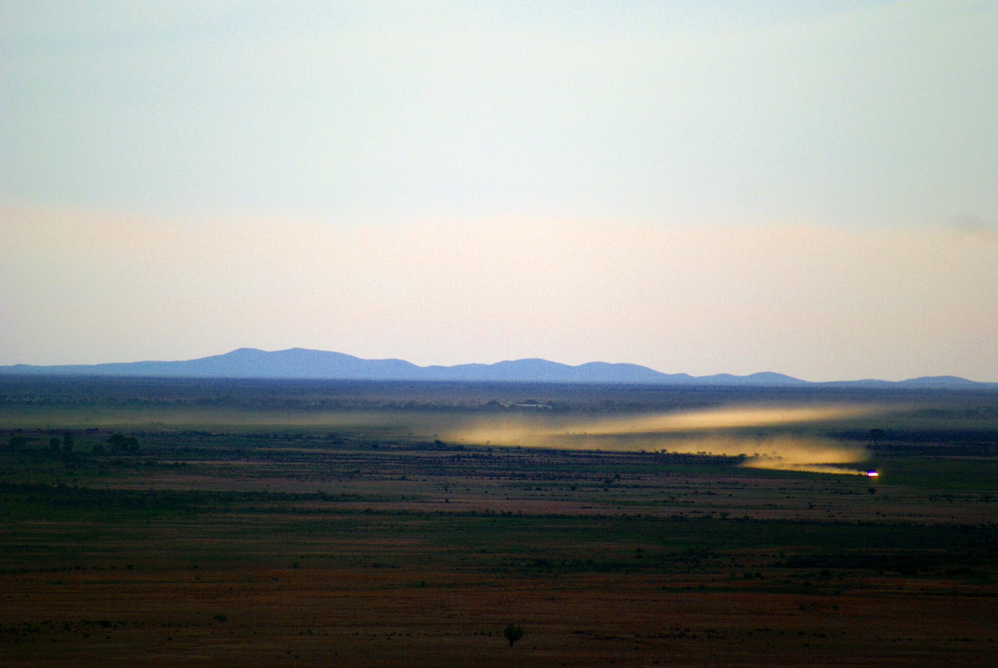 Photo of a dust trail from a distant car at dusk.