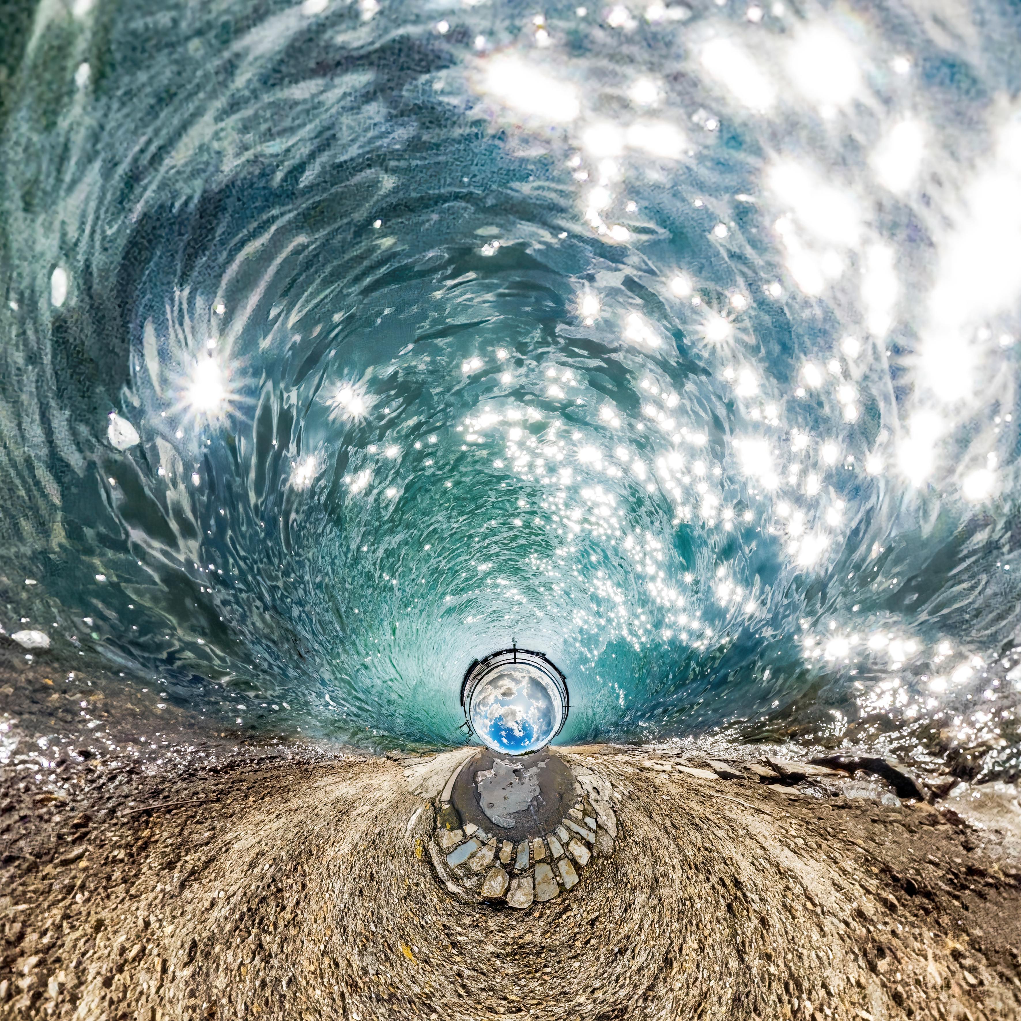 A vortex of swirling water with sunlight bursting on the surface.